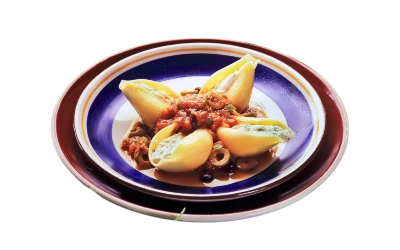 Conchiglione recheado com molho e azeitonas, em prato azul e vinho