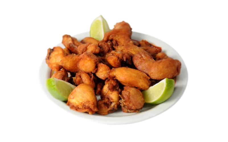 Frango à passarinho frito com fatias de limão, em prato branco