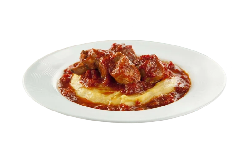 Frango ao molho de tomate sobre polenta cremosa, em prato branco